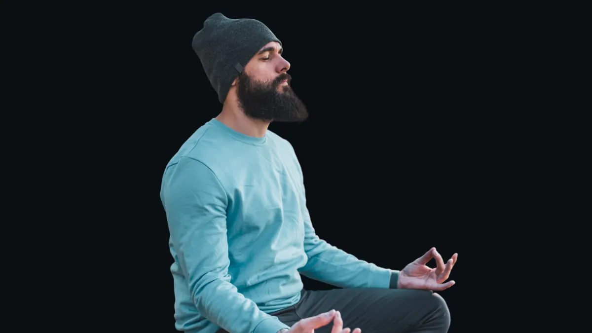 A man sitting cross legged, breathing slowly with his eyes closed