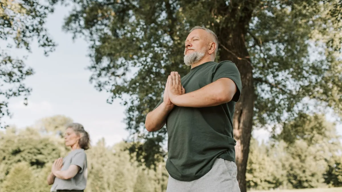 A man outdoors with his hands together, taking a slow breath